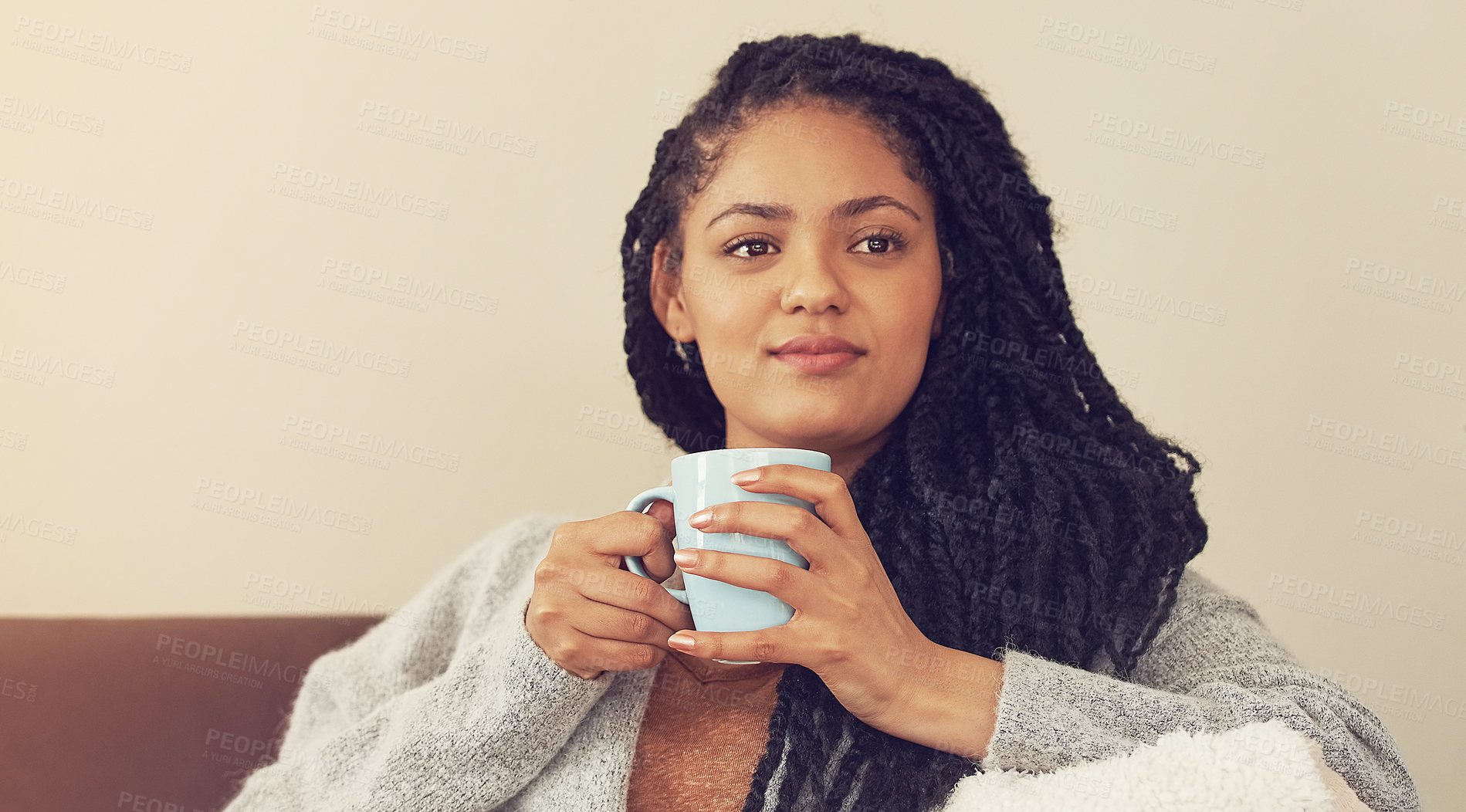 Buy stock photo Shot of a young woman enjoying a cup of coffee in her living room