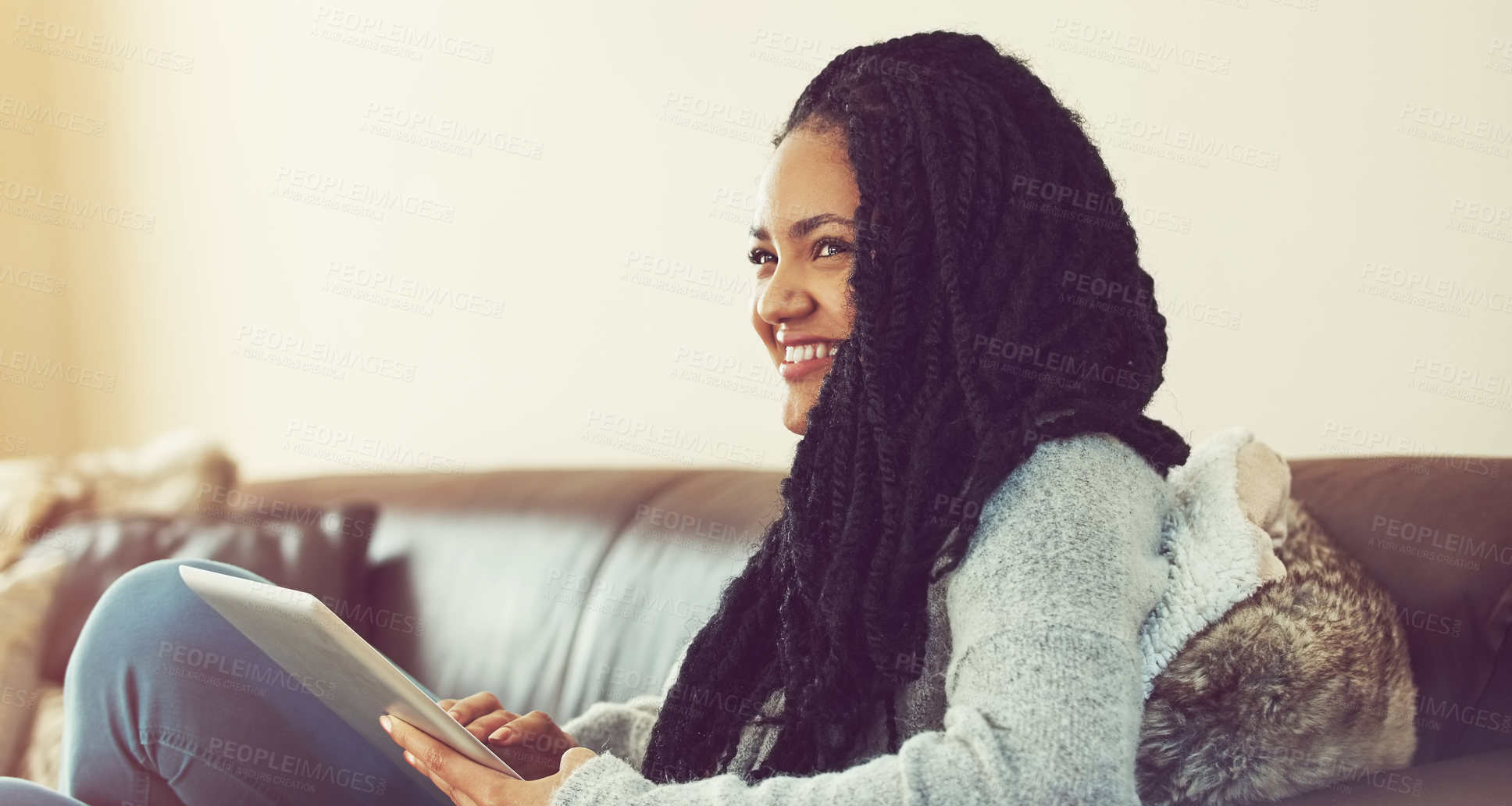 Buy stock photo Shot of a young woman using her tablet while relaxing at home