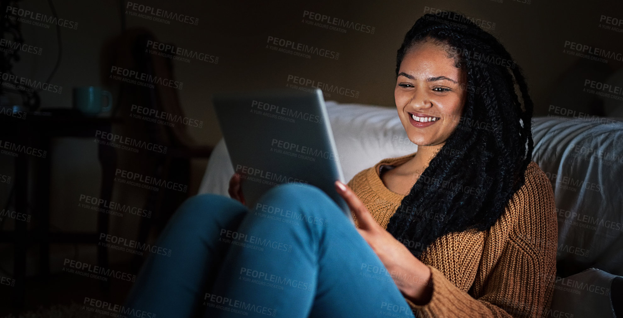 Buy stock photo Shot of a relaxed young woman using a digital tablet during the evening at home