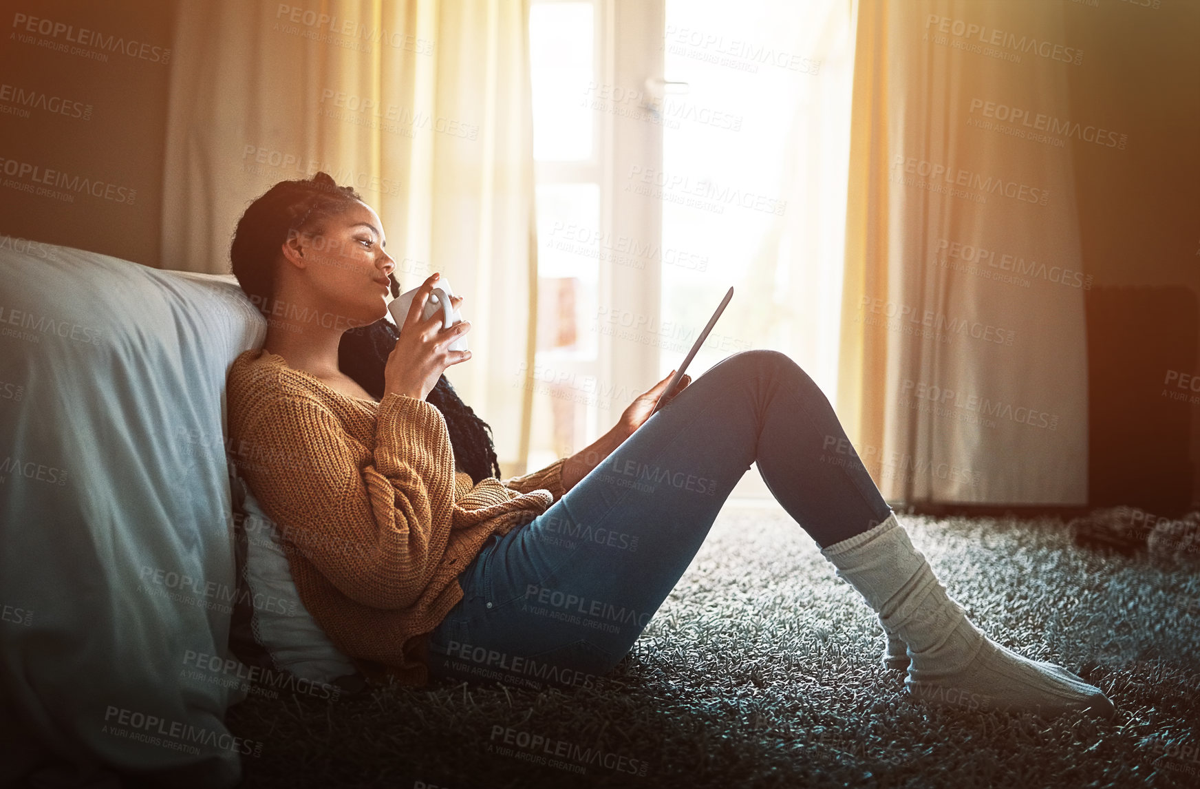 Buy stock photo Shot of a relaxed young woman drinking coffee and using a digital tablet at home