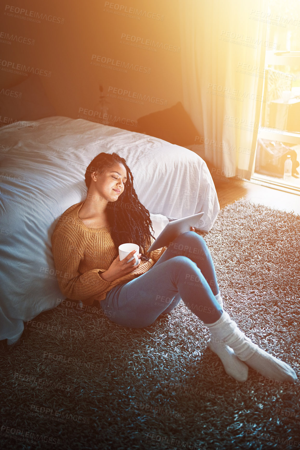 Buy stock photo Shot of a relaxed young woman drinking coffee and using a digital tablet at home