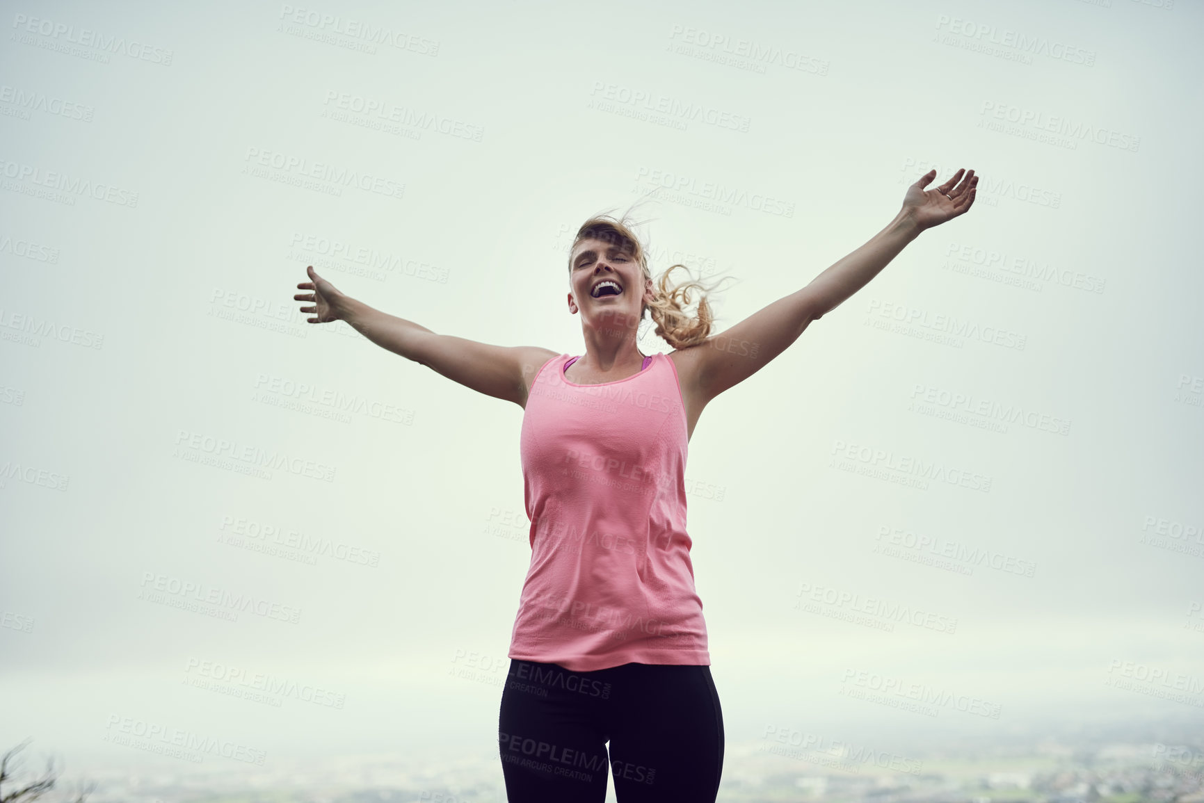 Buy stock photo Shot of a happy young woman feeling free while out for a run in the city