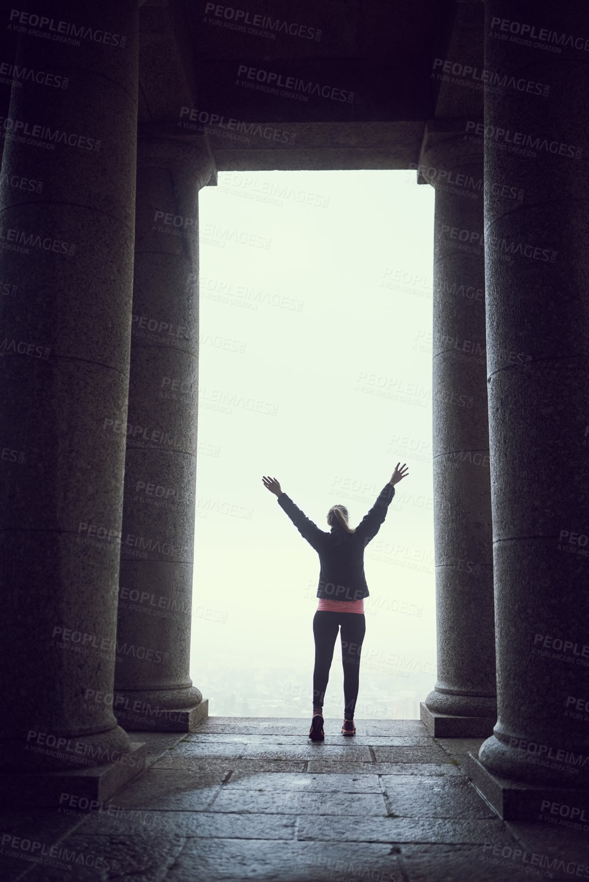 Buy stock photo Runner, back and celebration with fist, outdoor and city view by pillars with success, goals or progress for fitness. Person, cheers and achievement for training, exercise and workout for wellness