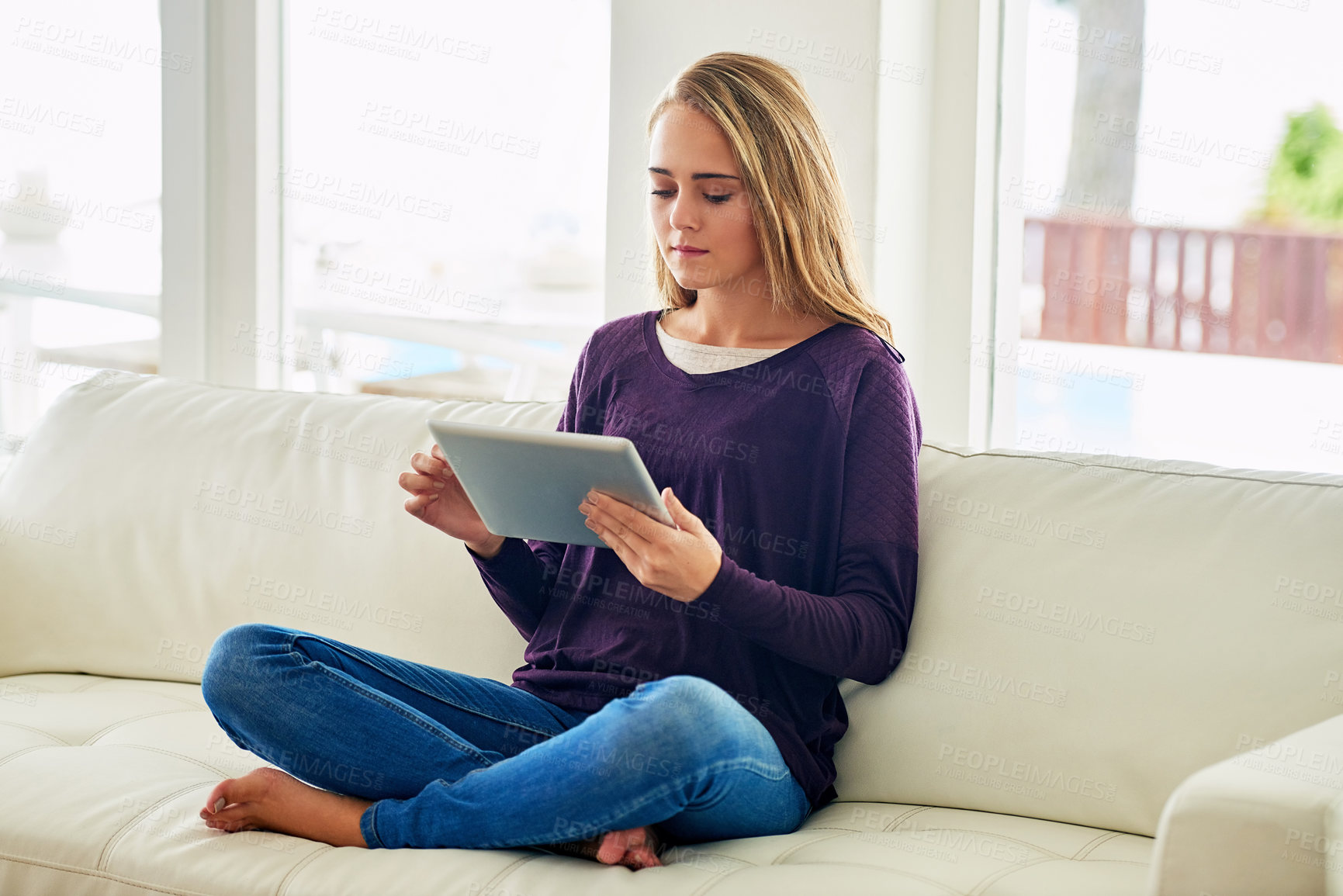 Buy stock photo Full length shot of an attractive young woman using her tablet while chilling at home