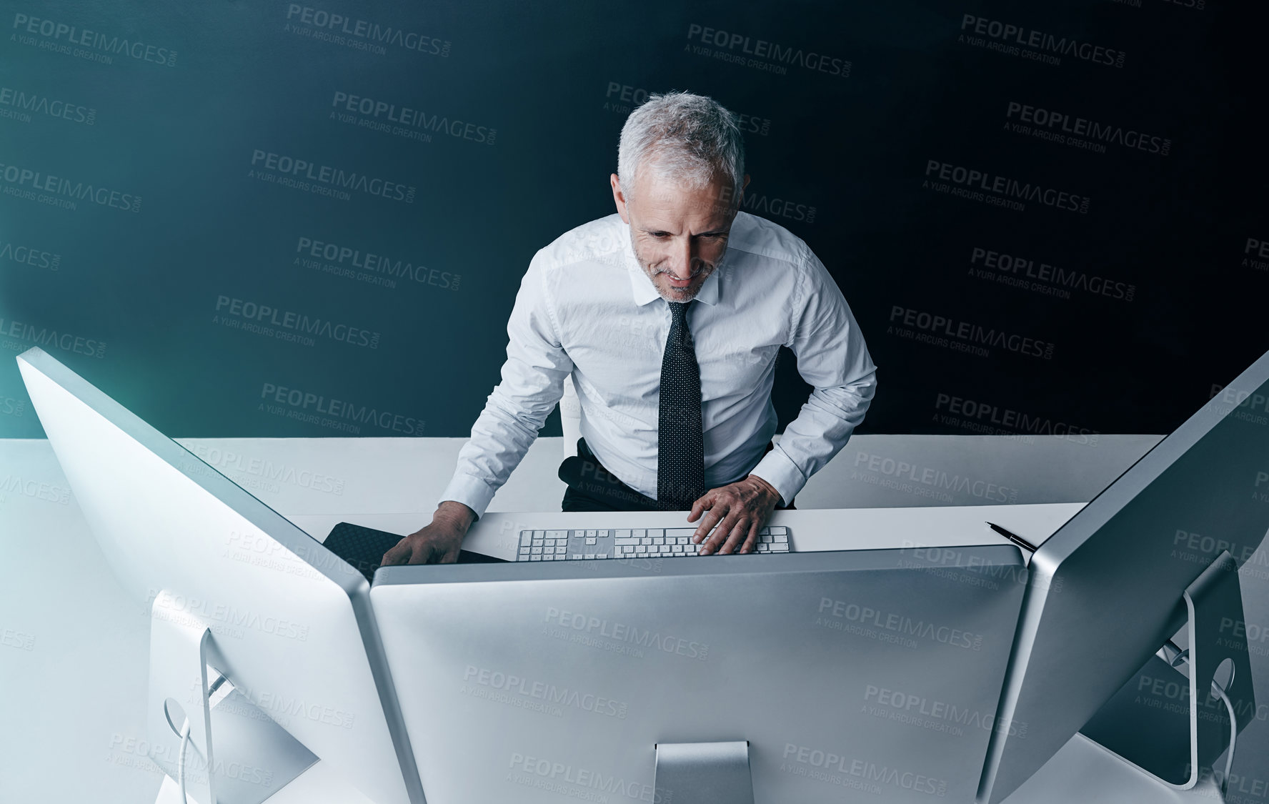 Buy stock photo High angle shot of a businessman working behind his computer in the office