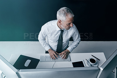 Buy stock photo High angle shot of a businessman working behind his computer in the office