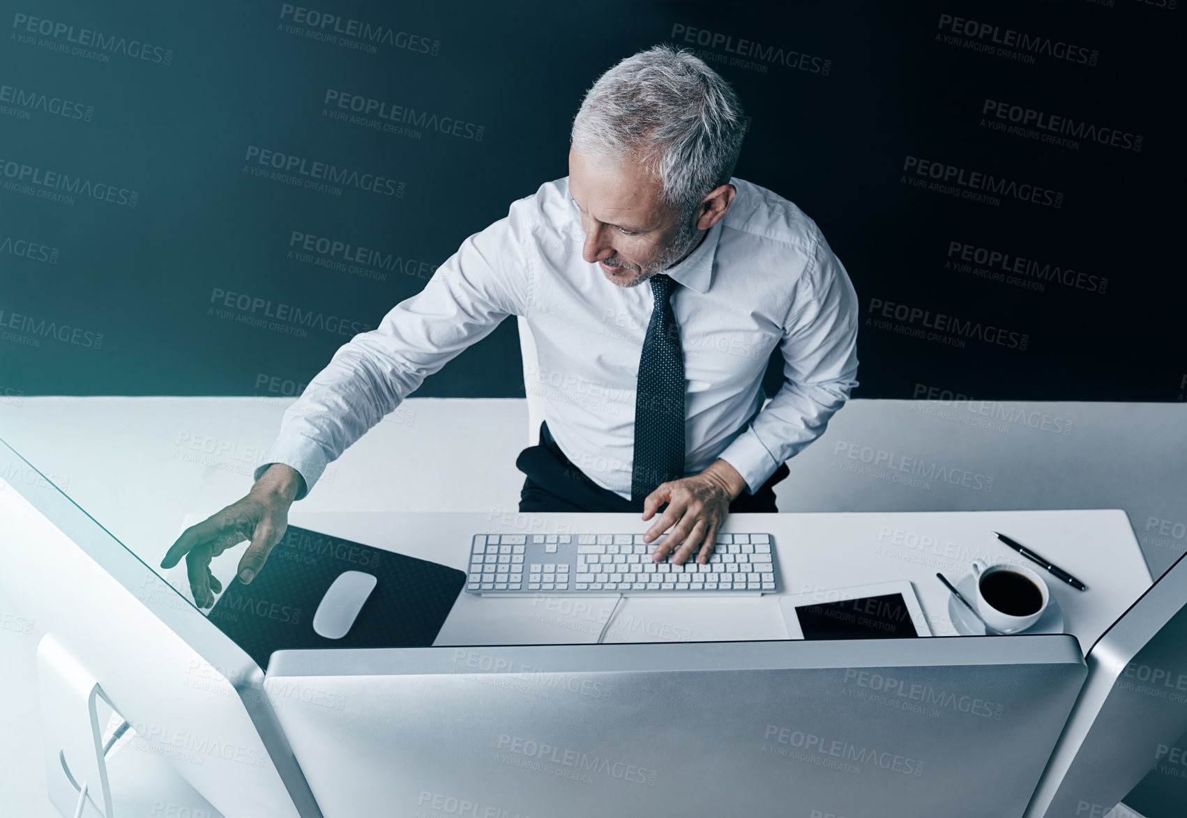 Buy stock photo High angle shot of a businessman working behind his computer in the office