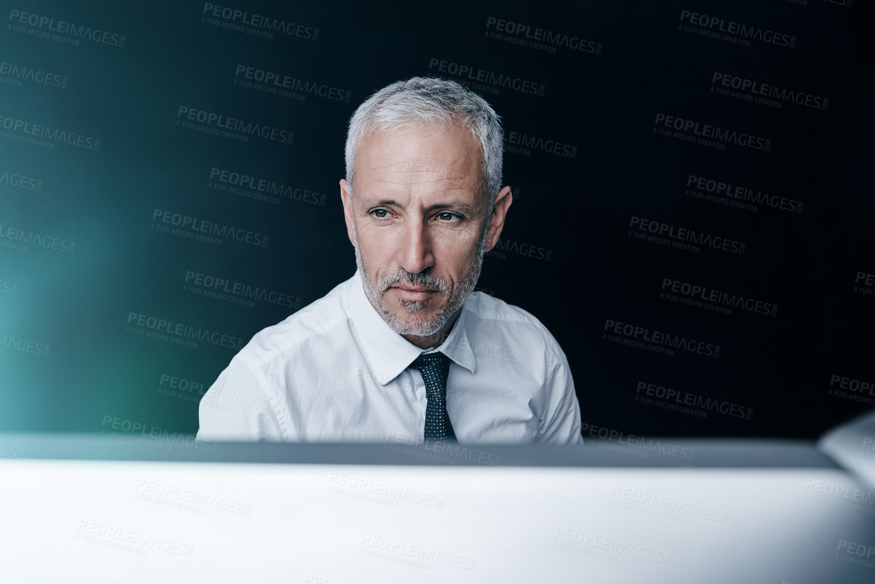 Buy stock photo Shot of a focussed businessman working behind his computer in the office