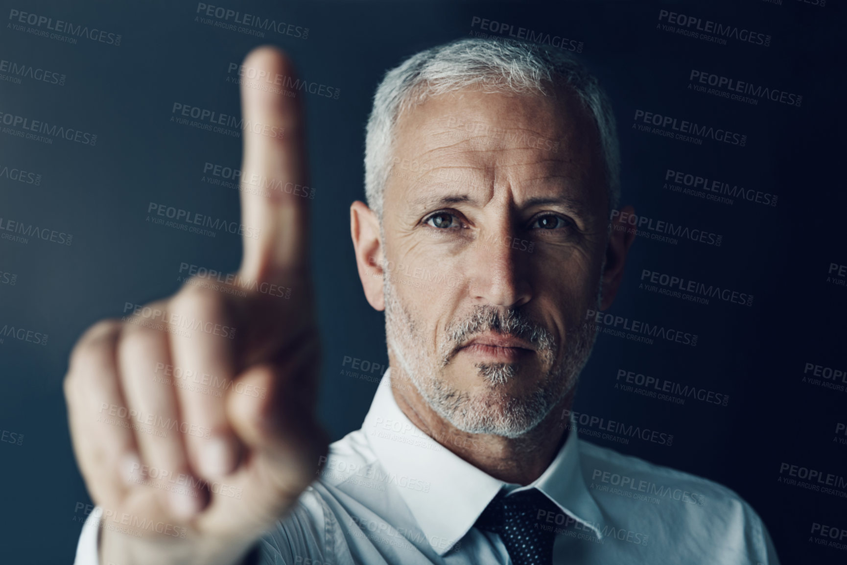 Buy stock photo Portrait of a focussed businessman holding up his finger as if using a touchscreen in the office
