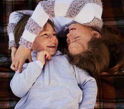 Buy stock photo High angle shot of a cute little girl hugging her brother while they lie on a blanket together