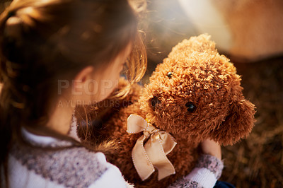 Buy stock photo Rearview shot of an unidentifiable little girl holding her teddy bear while playing outside