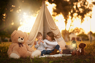 Buy stock photo Shot of two cute little siblings playing together in a teepee outside