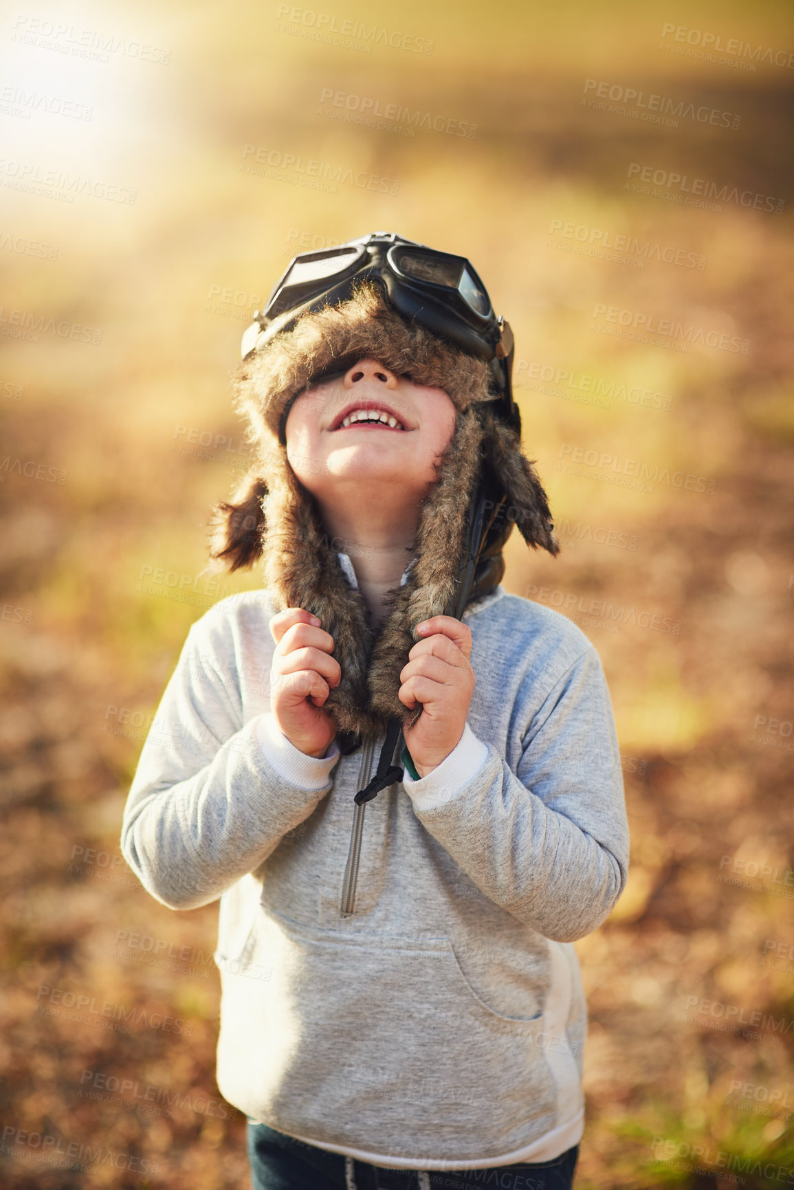 Buy stock photo Shot of a cute little boy wearing a pilot's hat and goggles while playing outside