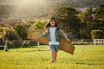 Buy stock photo Shot of a cute little boy wearing a pilot's hat and goggles while playing with cardboard wings outside