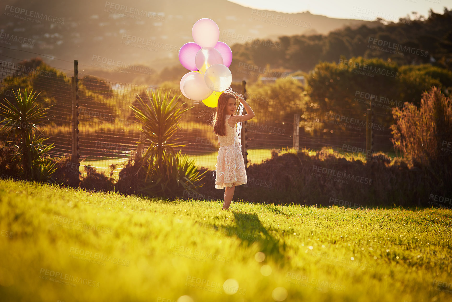 Buy stock photo Girl, outdoor and walking with balloons, portrait and happy for celebration of birthday, smile and grass. Backyard, event and party for child, excited or joy for gift in summer, nature and California