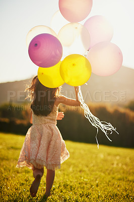 Buy stock photo Rearview shot of an unidentifiable little girl holding a big bunch of balloons while walking outside
