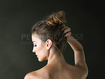 Buy stock photo Rearview shot of a beautiful young woman posing against a dark background