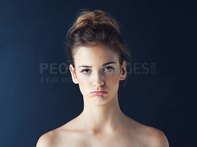 Buy stock photo Cropped shot of a beautiful young woman sulking against a blue background
