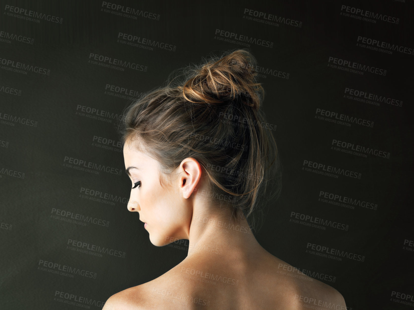 Buy stock photo Rearview shot of a beautiful young woman posing against a dark background