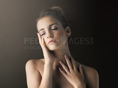 Buy stock photo Studio shot of a beautiful young woman touching her soft skin against a dark background