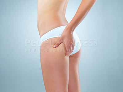 Buy stock photo Person, studio and hand on buttocks for lose weight or body treatment, transformation or metabolism for health. Blue background, legs and pinch bum with cellulite, skin results and wellness.