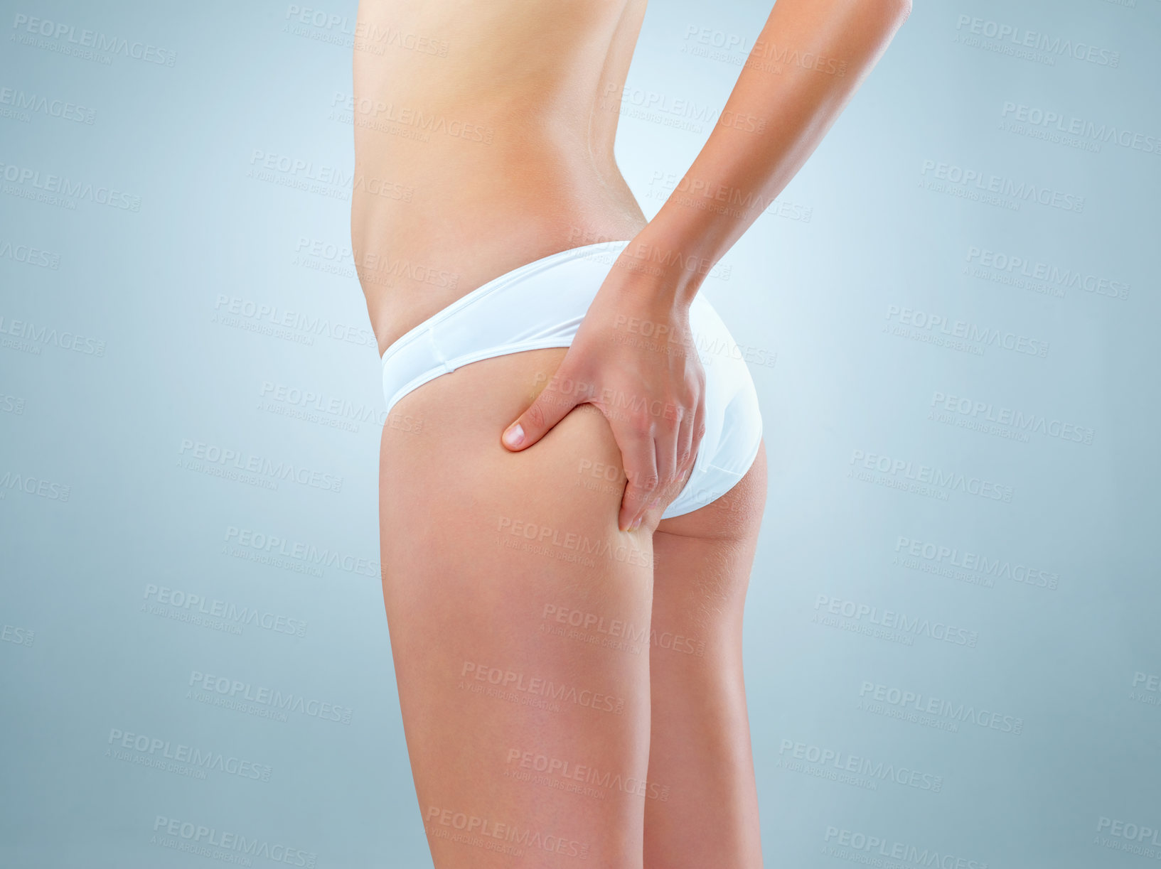 Buy stock photo Person, studio and hand on buttocks for lose weight or body treatment, transformation or metabolism for health. Blue background, legs and pinch bum with cellulite, skin results and wellness.