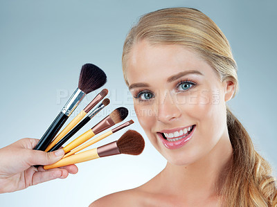 Buy stock photo Woman, portrait and cosmetic brushes in studio, transformation and choice on blue background. Female person, skincare and makeup tools or collection, facial treatment and decision for dermatology