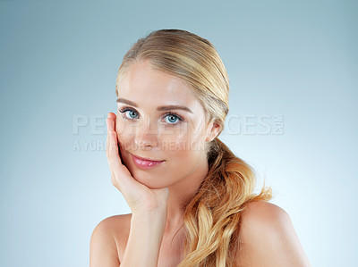 Buy stock photo Studio portrait of a beautiful young blonde woman posing against a blue background