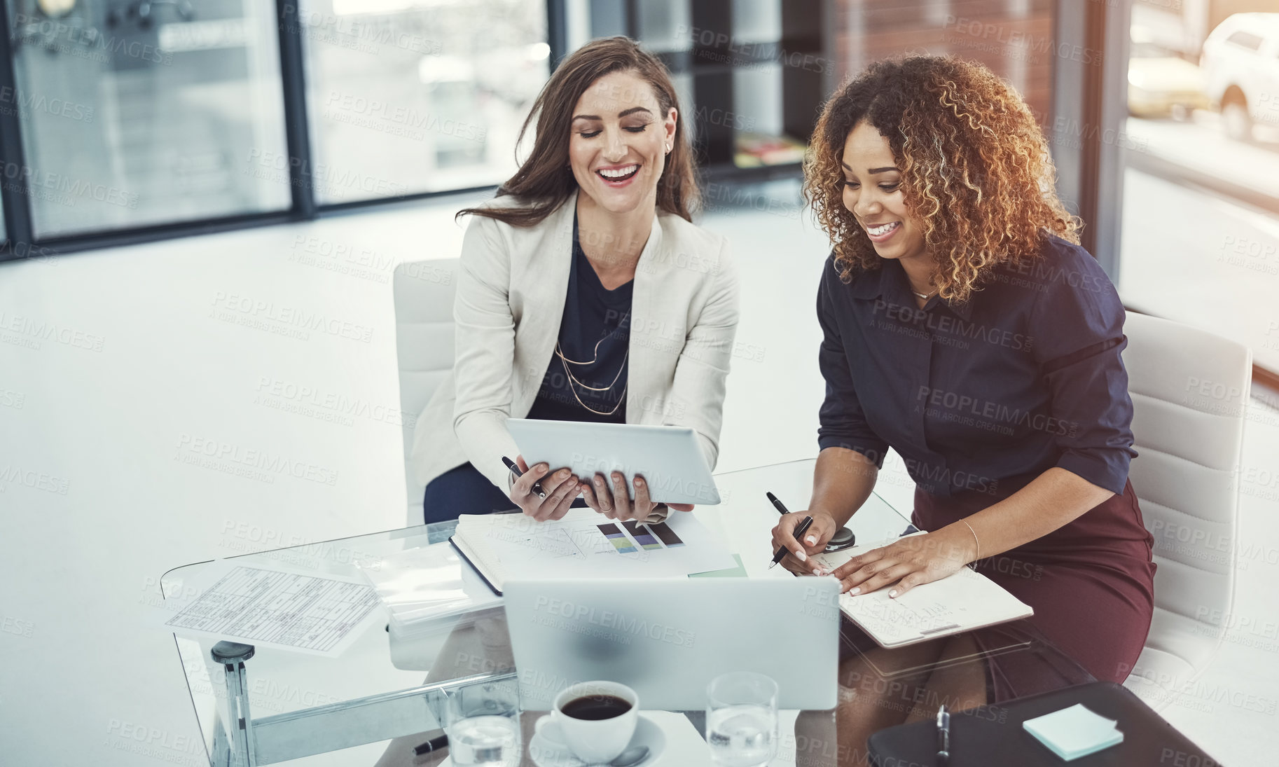 Buy stock photo Shot of two businesswomen discussing something on a digital tablet