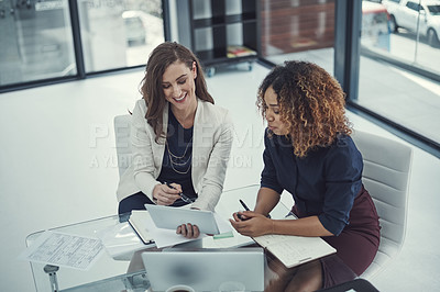Buy stock photo Shot of two businesswomen discussing something on a digital tablet