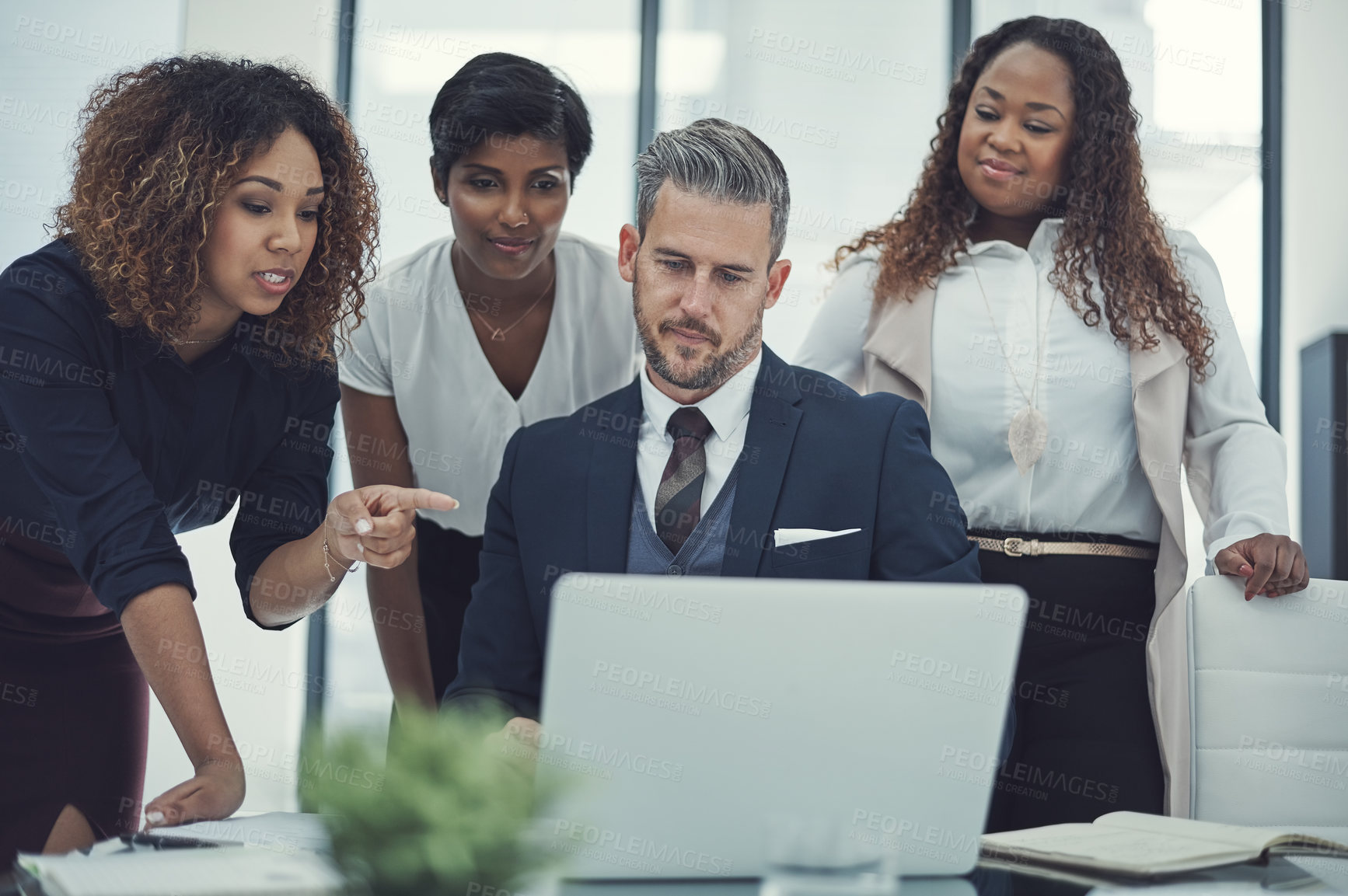 Buy stock photo Shot of a group of colleagues using a laptop together in a modern office