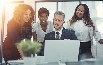 Buy stock photo Shot of a group of colleagues using a laptop together in a modern office