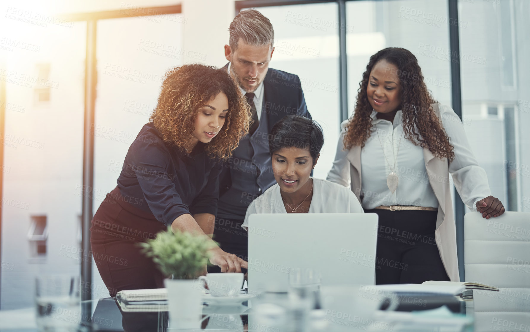 Buy stock photo Shot of a group of colleagues using a laptop together in a modern office