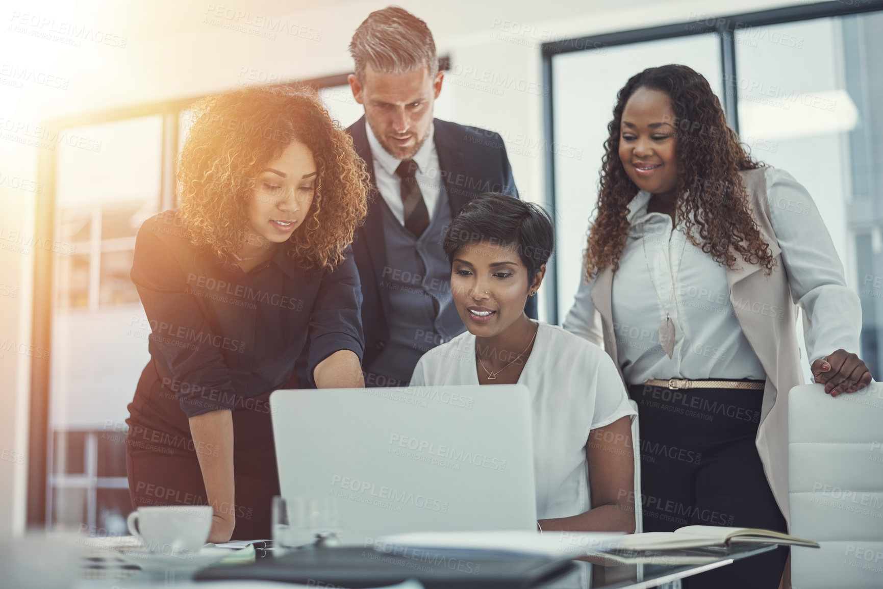 Buy stock photo Shot of a group of colleagues using a laptop together in a modern office