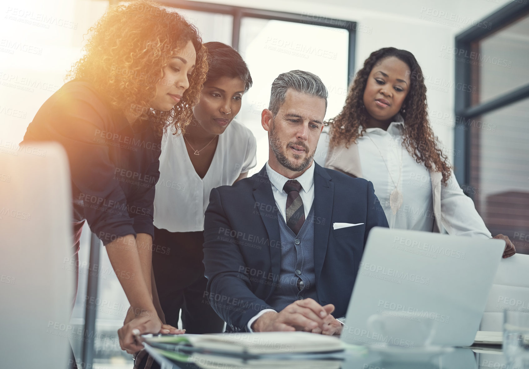 Buy stock photo Shot of a group of colleagues using a laptop together in a modern office