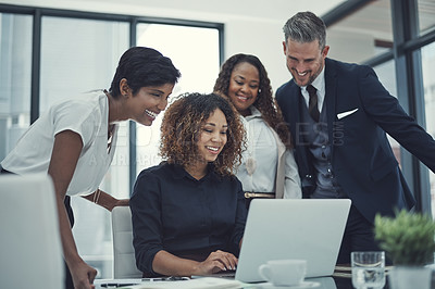 Buy stock photo Shot of a group of colleagues using a laptop together in a modern office