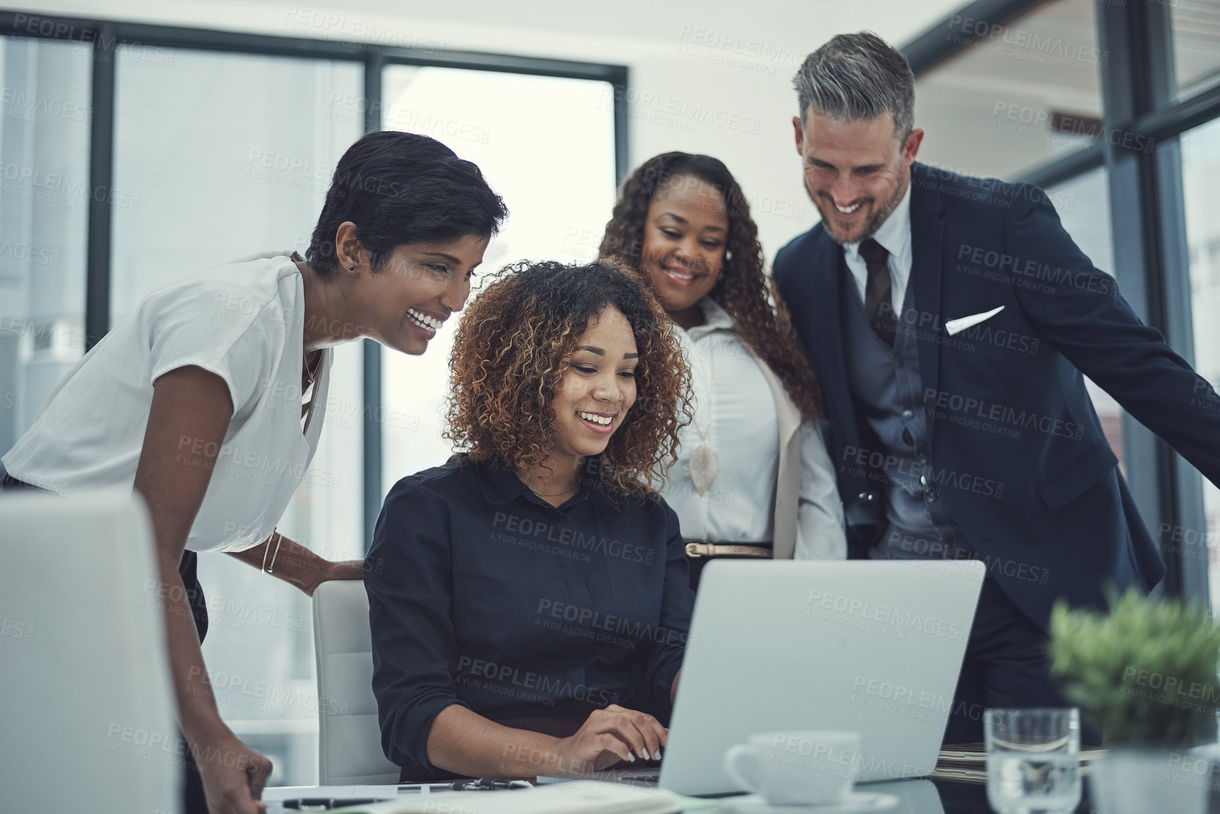 Buy stock photo Shot of a group of colleagues using a laptop together in a modern office