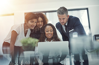 Buy stock photo Shot of a group of colleagues using a laptop together in a modern office