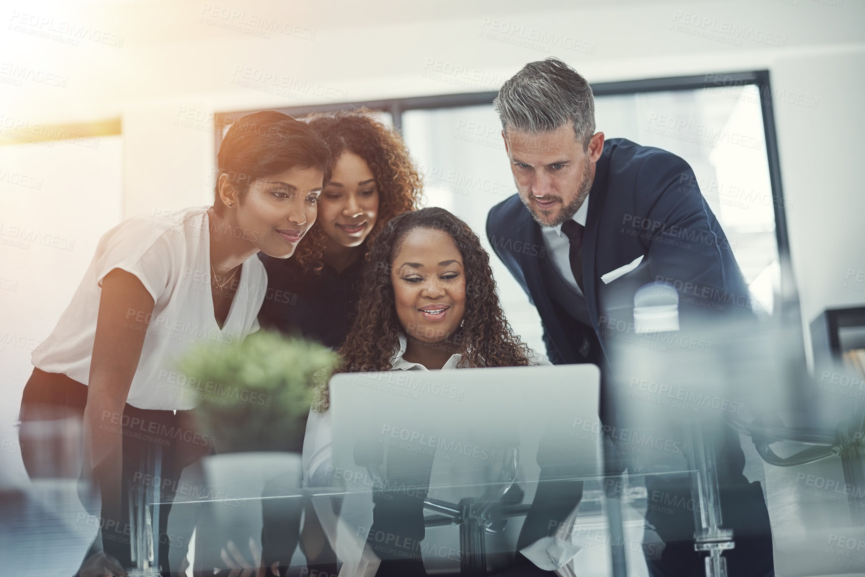 Buy stock photo Shot of a group of colleagues using a laptop together in a modern office