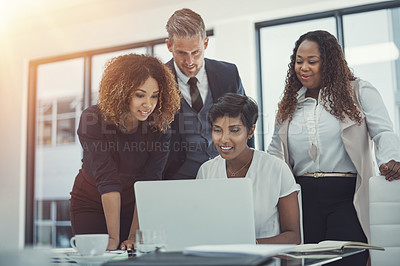 Buy stock photo Shot of a group of colleagues using a laptop together in a modern office