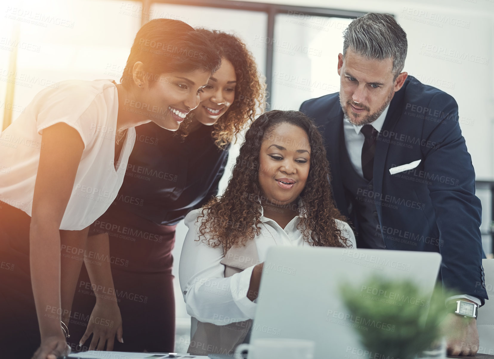 Buy stock photo Shot of a group of colleagues using a laptop together in a modern office