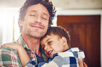 Buy stock photo Cropped shot of a father hugging his little son at home