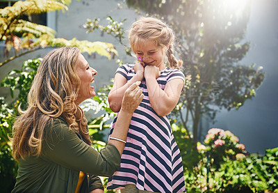 Buy stock photo Happy, girl and mom with flower in garden for playful humour, love and childhood development. Woman, smile and daughter with plants in backyard for motherhood care, summer fun and bonding together