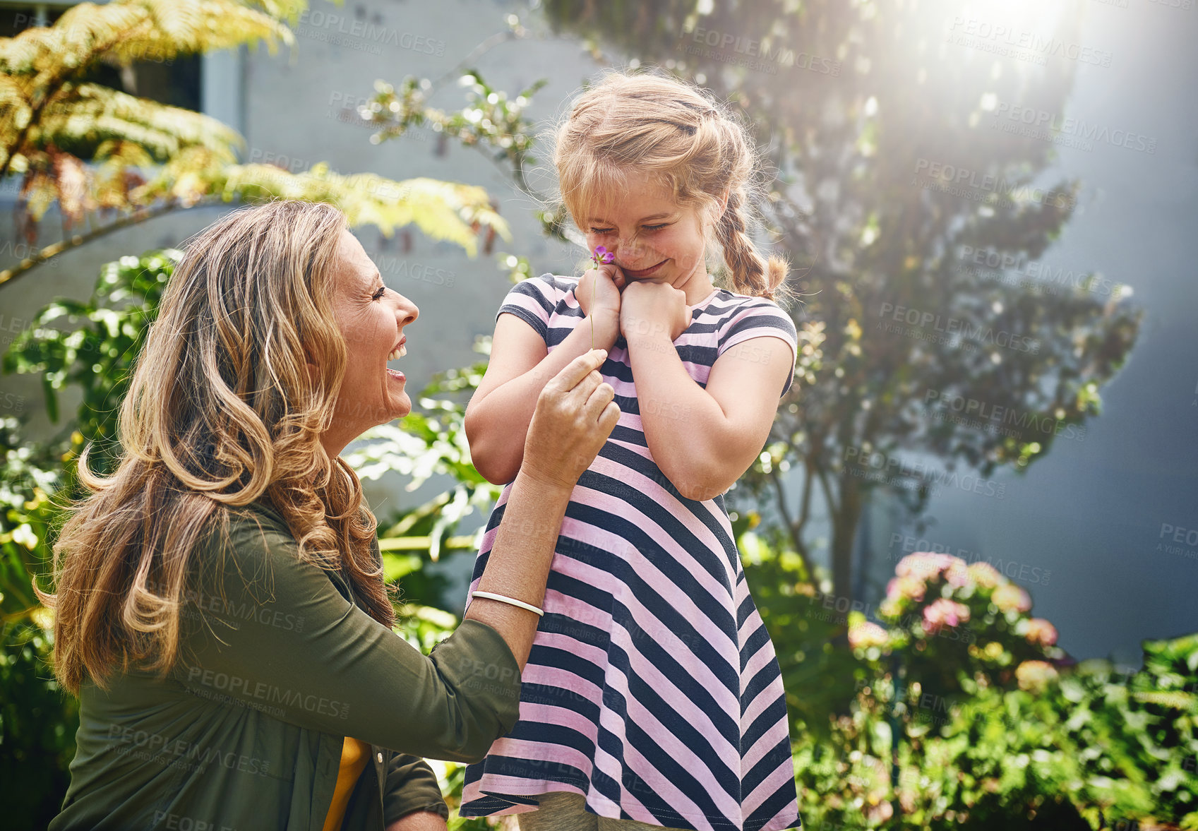 Buy stock photo Happy, girl and mom with flower in garden for playful humour, love and childhood development. Woman, smile and daughter with plants in backyard for motherhood care, summer fun and bonding together