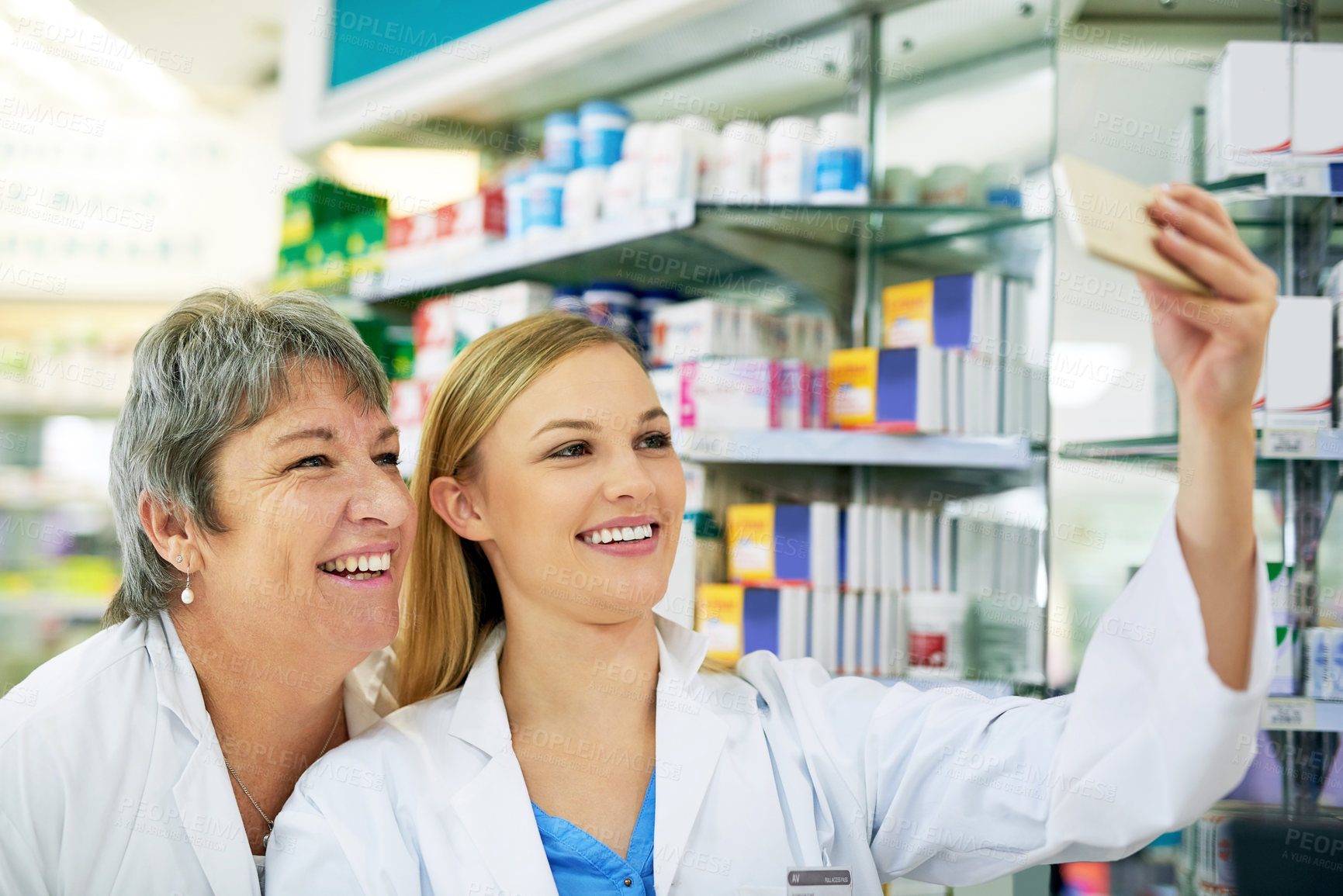 Buy stock photo Shot of two happy pharmacists taking a selfie together in a chemist
