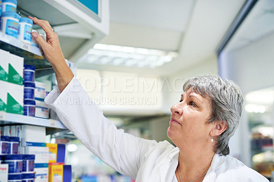 Buy stock photo Shot of a pharmacist looking through the shelves at a chemist