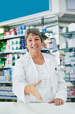 Buy stock photo Portrait of a happy mature pharmacist extending her arm for a handshake
