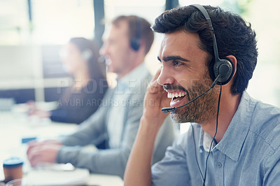 Buy stock photo Cropped shot of a call centre agent working in an office with his colleagues in the background