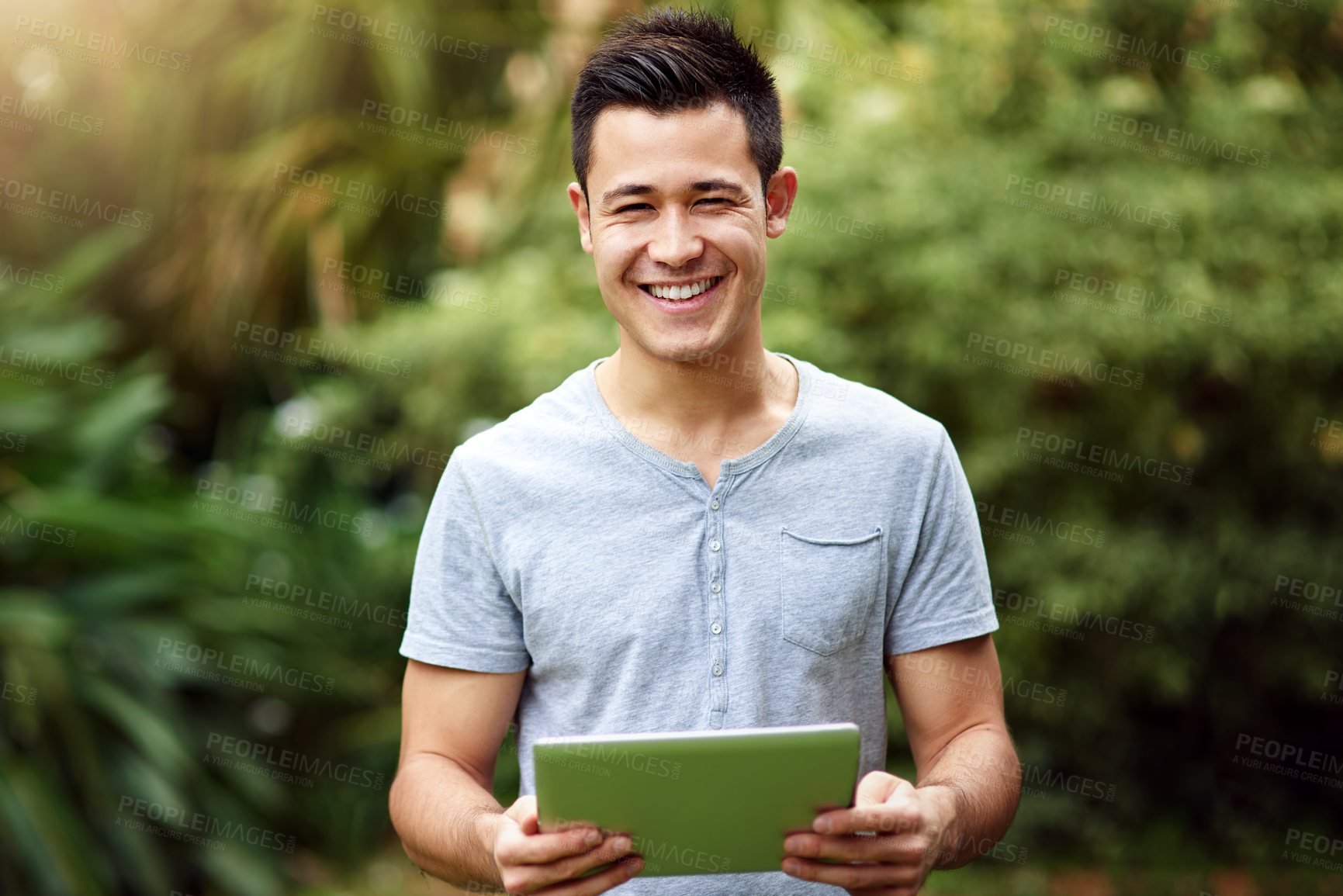 Buy stock photo Portrait of a handsome young man using a digital tablet outside