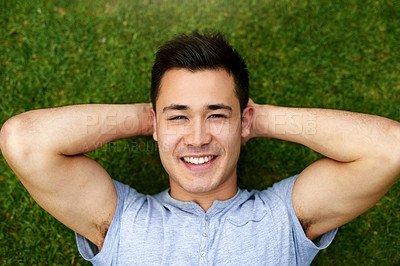 Buy stock photo Portrait of a handsome young man relaxing on the grass outdoors